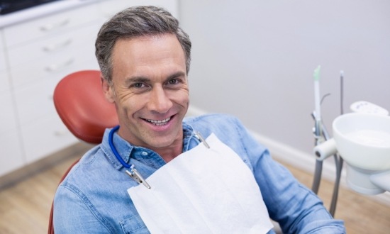 Smiling man in denim shirt sitting in dental chair