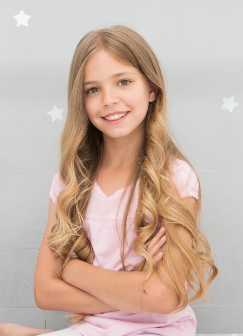 Young girl with long blonde hair smiling after visiting childrens dentist