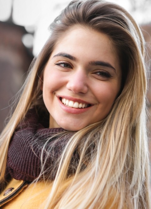 Blonde woman with scarf smiling after cosmetic dentistry in Stephenville and Eastland