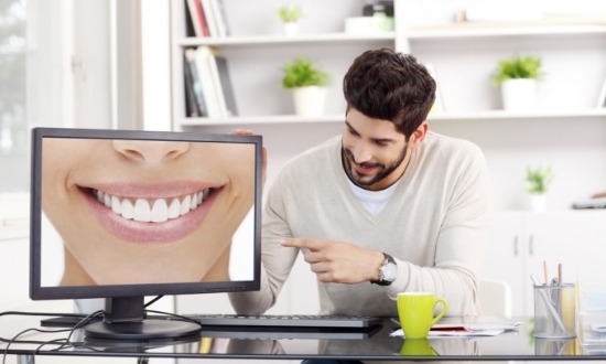 Man pointing to computer screen showing close up of flawless smile