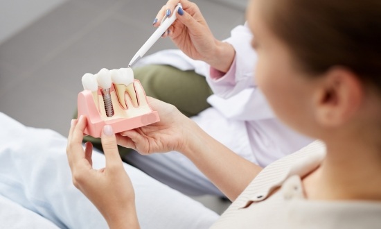 Dentist showing a model of a dental implant to a patient