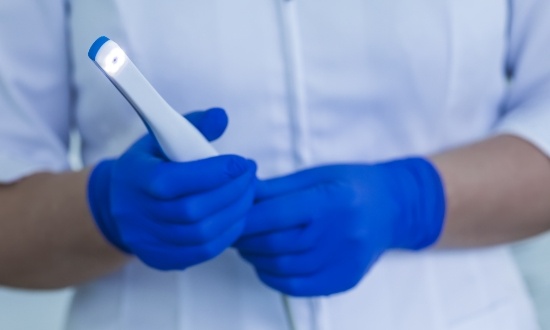 Dental team member holding a white pen like intraoral camera