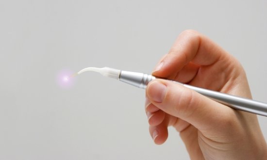 Hand holding a thin metal dental laser device