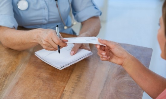 Person handing a paper check to someone across a desk