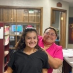 Two smiling dental team members standing in reception area