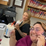 Two dental team members with milkshakes sitting at desk