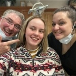 Dentist and assistant pointing to a smiling patient