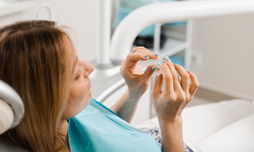 Closeup of patient holding clear aligner in treatment chair