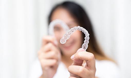 Smiling patient holding clear aligner