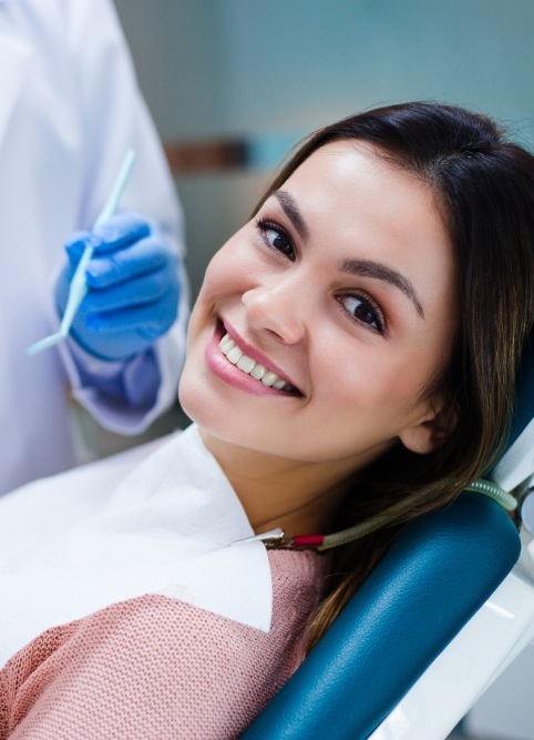 Smiling woman leaning back in dental chair during preventive dentistry checkup