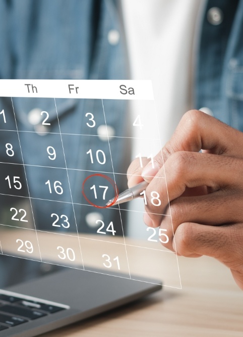 Person circling date of dental appointment on holographic calendar