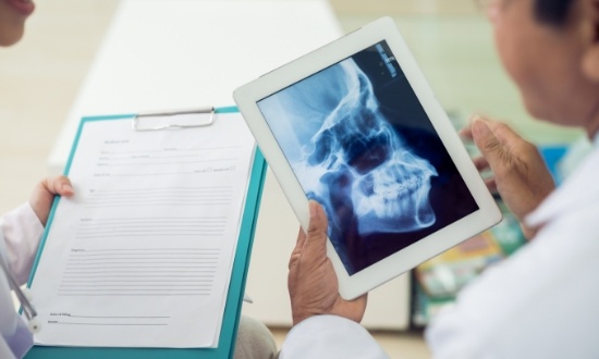 Two dentists looking at x ray of a skull